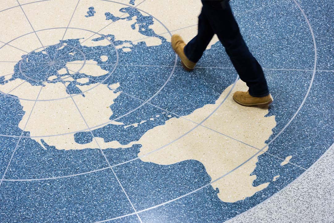 Person walking over globe on tile floor