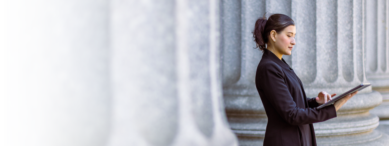 A woman looking at a document in between marble pillars.